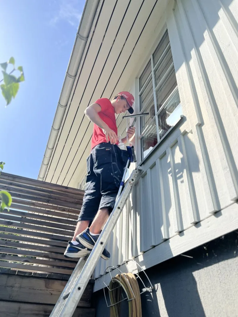 Klas klättrar upp för stege för fönsterputs
